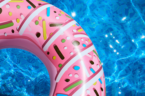Summer vibes: a pink doughnut pool inner tube floats in a bright blue pool
